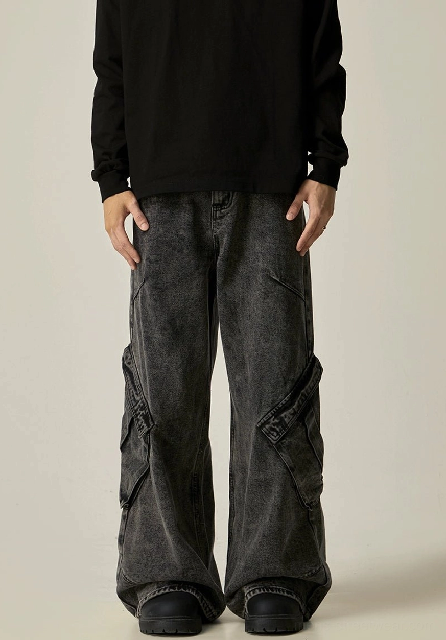 Front lower-body view of vintage washed black cargo denim pants with decorative side pocket flaps and loose wide-leg styling