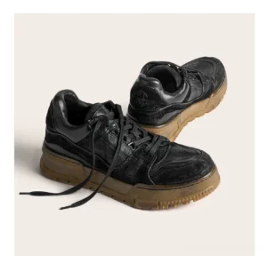 Washed black vintage chunky sneakers with distressed horsehide leather upper, cream laces, and thick gum rubber outsole on a beige background
