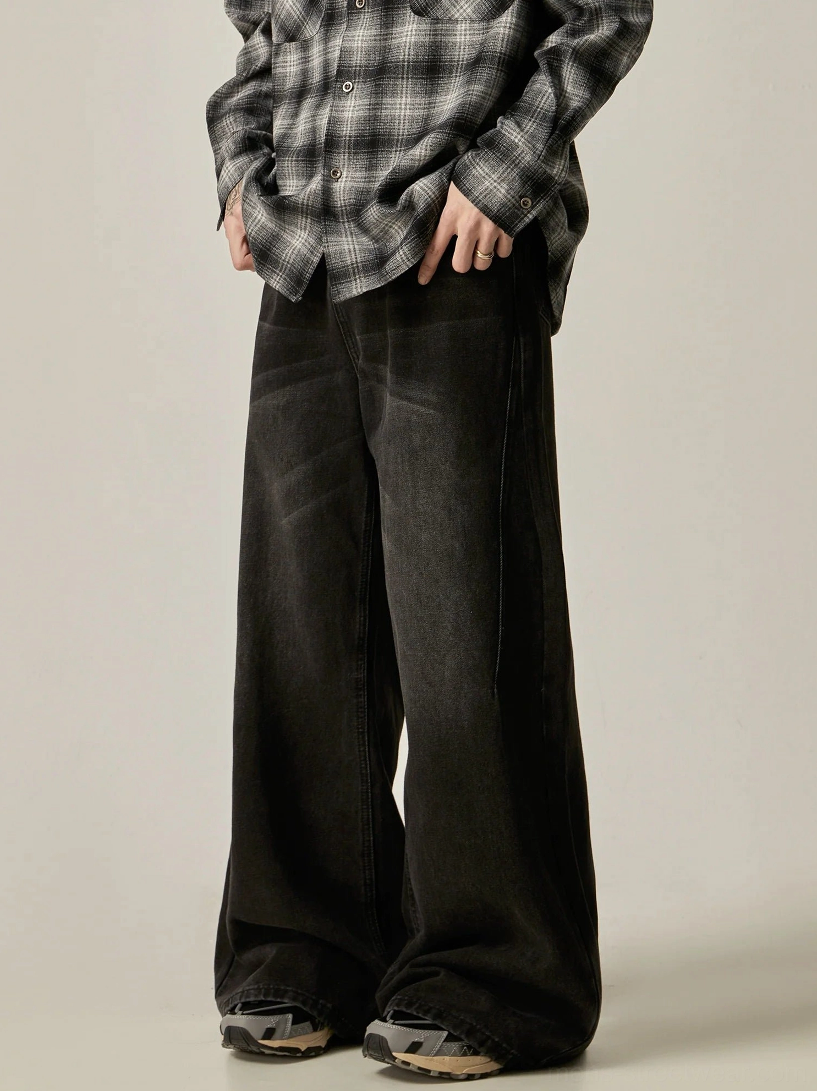 Side front view of vintage washed black wide-leg denim jeans with relaxed Korean streetwear styling and casual sneakers