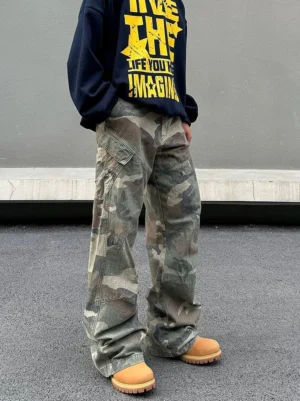 Vintage washed camouflage wide leg cargo pants styled with a navy graphic hoodie and tan work boots in an outdoor streetwear front three-quarter view