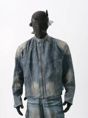 Front view of a vintage washed denim moto jacket in faded denim blue with stand collar, metal front zipper, slanted chest zip pockets, sculpted shoulder panels, and matching streetwear cargo pants
