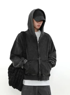 Vintage washed faded charcoal black zip-up hoodie worn by male streetwear model in a three-quarter front view with cargo pants