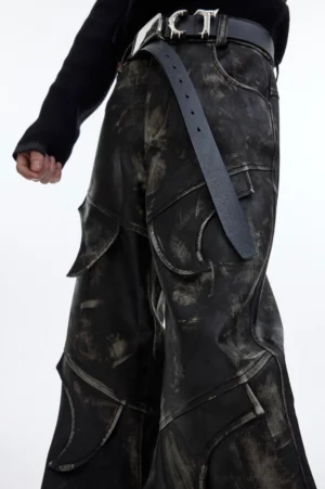 Close-up side detail of distressed faux leather flare cargo pants with stitched panels and metal buckle belt