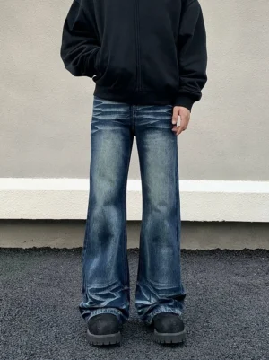 Front low angle view of men's vintage washed blue flare jeans with ultra-wide legs, thigh fading, stacked hems, black hoodie, chunky work boots, and Korean streetwear styling