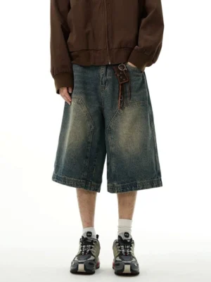 Front full-body view of blue vintage washed wide-leg denim shorts with oversized patch pockets styled with a brown zip-up jacket and sneakers