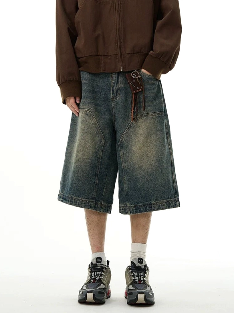 Front full-body view of blue vintage washed wide-leg denim shorts with oversized patch pockets styled with a brown zip-up jacket and sneakers