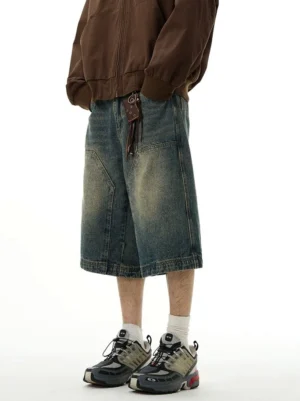 Low-angle front view of relaxed blue baggy denim shorts featuring faded wash, wide legs, large patch pockets, and leather belt accessory