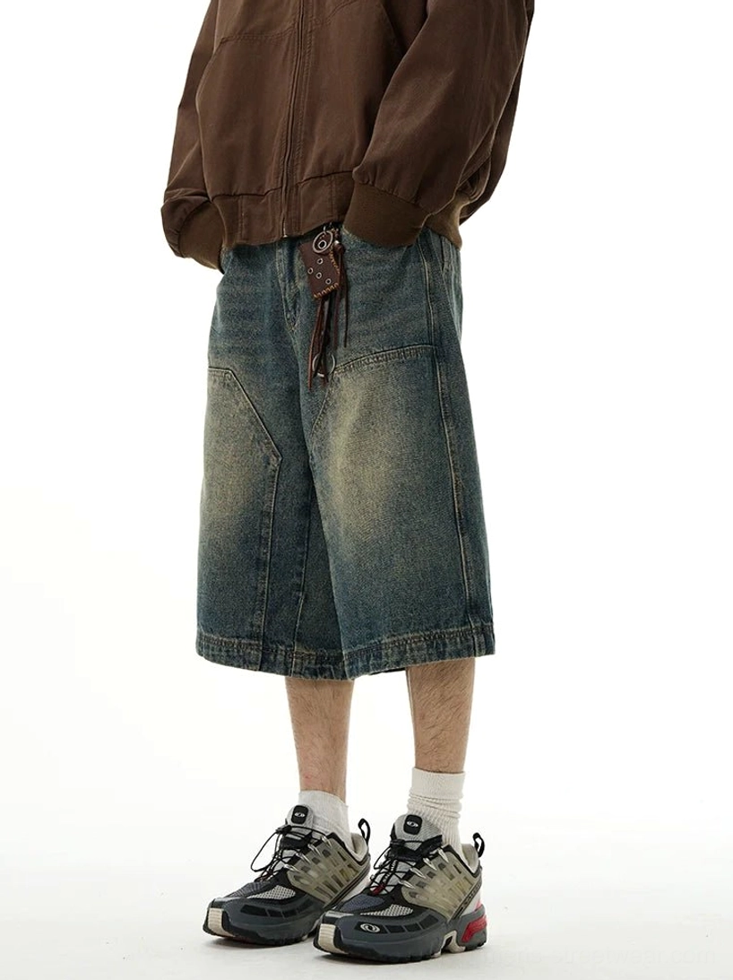Low-angle front view of relaxed blue baggy denim shorts featuring faded wash, wide legs, large patch pockets, and leather belt accessory