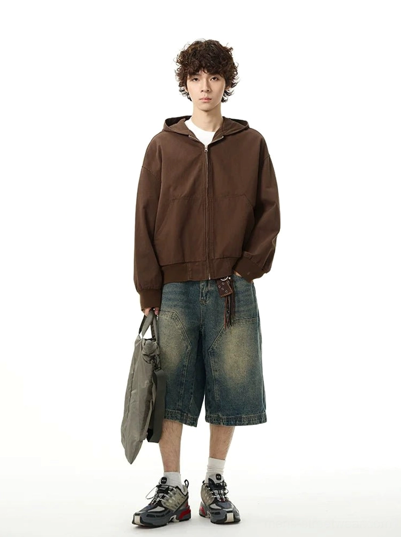 Full-body mens streetwear outfit featuring blue vintage washed baggy denim shorts, brown zip hoodie, canvas bag, and sporty sneakers