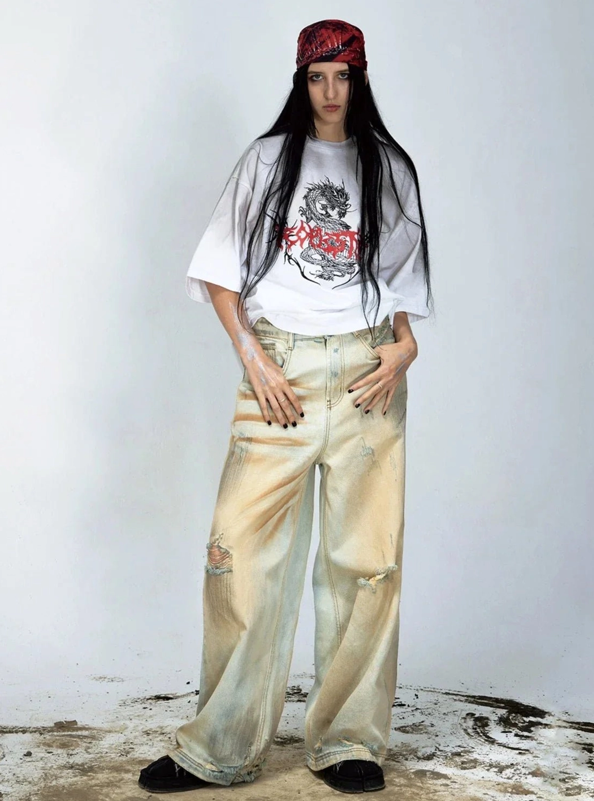 Full body female model wearing vintage yellow washed ripped wide-leg denim jeans in neutral studio