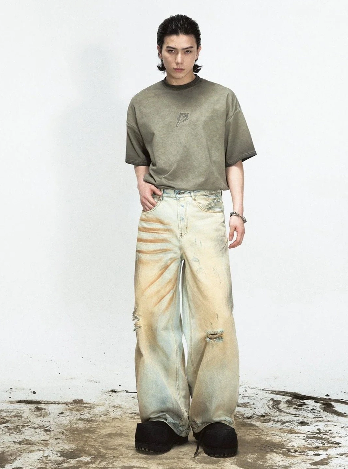 Male model wearing vintage yellow wide-leg distressed denim pants with oversized olive T-shirt