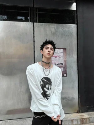 White oversized monochrome portrait long sleeve streetwear tee styled with layered necklaces in front of an industrial door