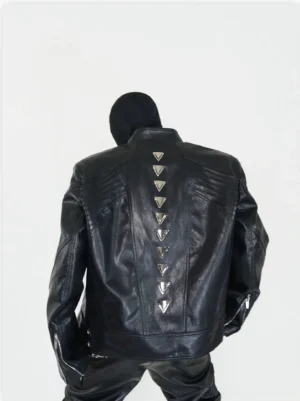 Black oversized PU leather biker jacket with vertical pyramid stud spine detail shown from the full back in a minimalist studio