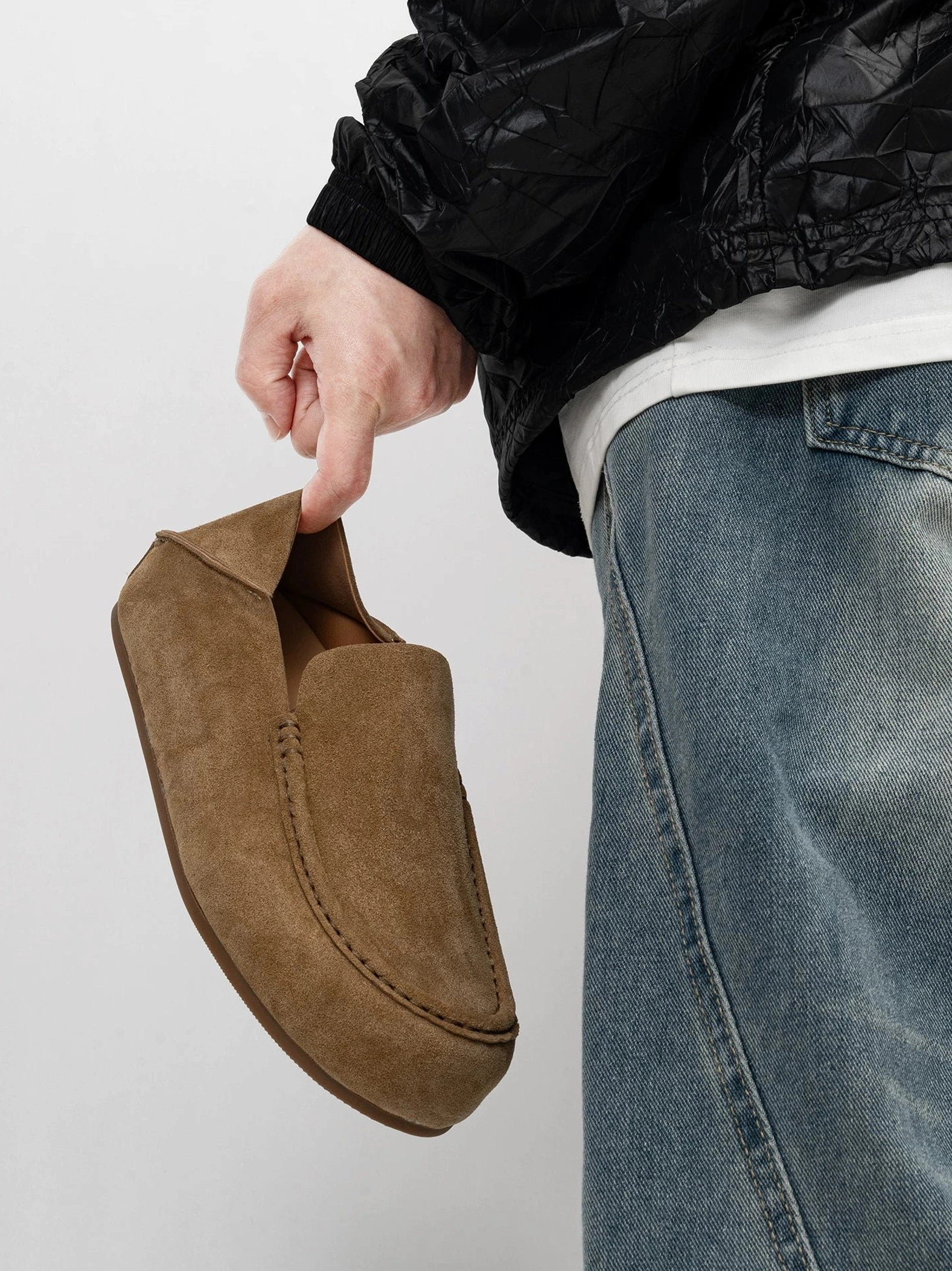 Warm brown suede moc toe loafers styled with blue jeans, black jacket, and white t shirt