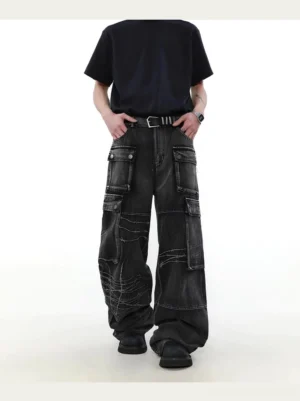 Front full-body view of washed black barbed wire wide-leg cargo denim jeans styled with a black t-shirt, belt, and chunky black boots