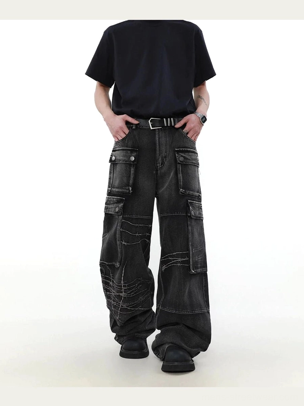 Front full-body view of washed black barbed wire wide-leg cargo denim jeans styled with a black t-shirt, belt, and chunky black boots