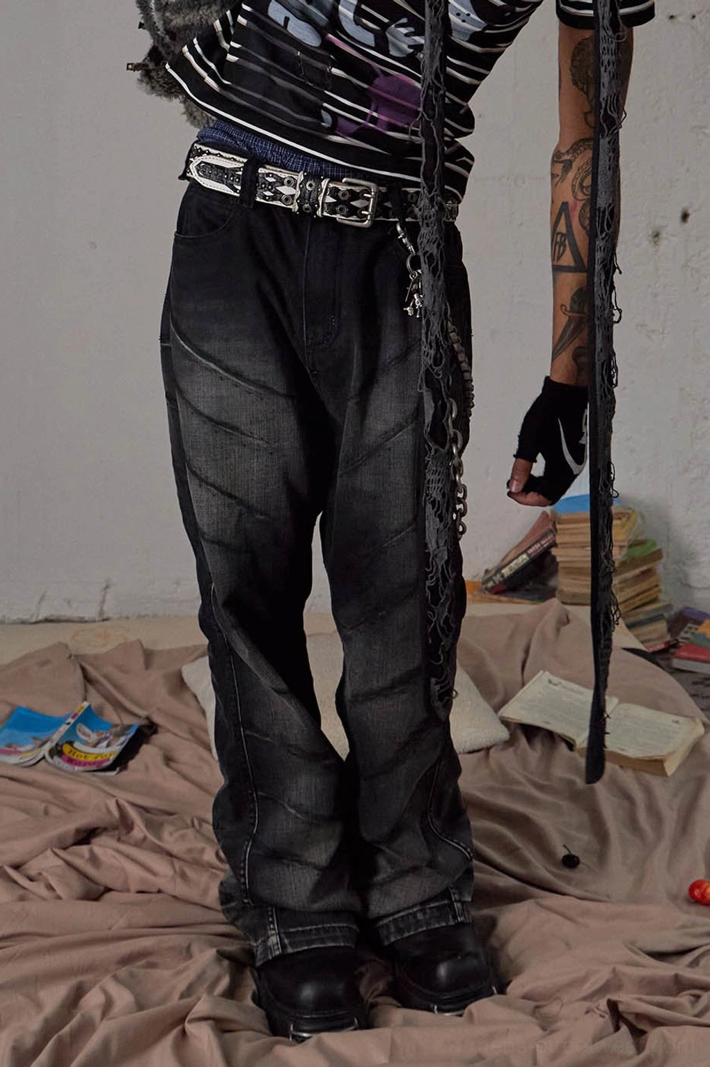 Front lower-body view of washed black flared streetwear jeans with chain accessory and wide leg opening