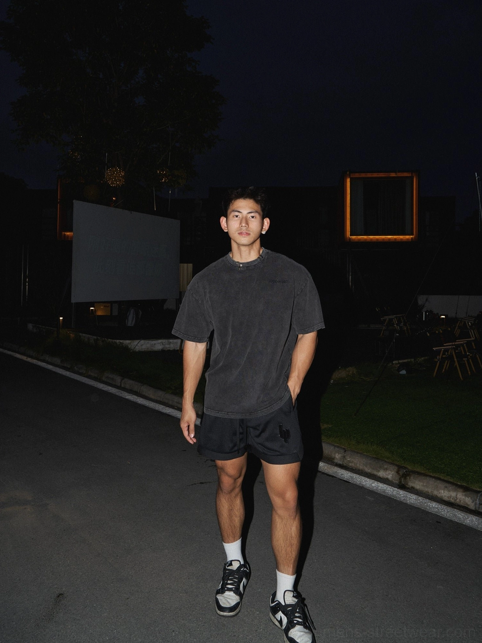 Washed black cotton oversized T-shirt with vintage faded finish styled with black athletic shorts for a casual urban streetwear look