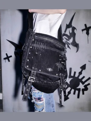 Washed black denim cyberpunk leg bag with heartbeat embroidery metal eyelets rivets and studded straps worn with ripped jeans