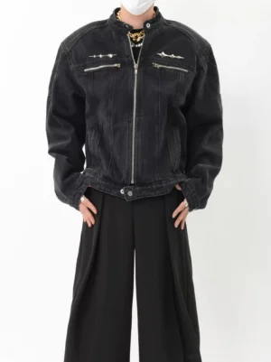 Front full body view of washed black denim moto jacket with silver zip pockets metal spike details and relaxed streetwear fit