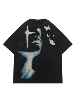 Washed black face art oversized graphic tee front flat lay with blue side profile face print cross star motif and white butterfly graphics