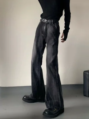 Washed black flare jeans shown from a low front three quarter angle with a slim longline streetwear silhouette and stacked legs over chunky black shoes