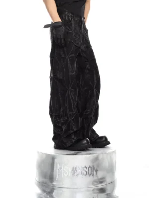 Three-quarter view of washed black fracture crinkle denim pants showing the geometric cracked texture and relaxed wide-leg Korean streetwear fit