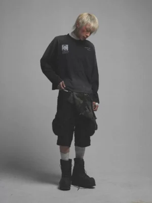 Front three quarter view of a washed black graphic long sleeve mock neck tee with chest print, gradient faded hem, and relaxed drop shoulder streetwear fit