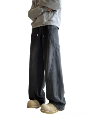Washed black-gray wide-leg streetwear sweatpants shown from a low front angle with oversized patch pockets, diagonal seam detailing, drawstring waist, gray sweatshirt, and platform loafers