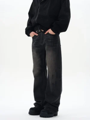Three-quarter view of washed black straight loose jeans showing relaxed fit, faded creases, belt loops, and leather belt styling