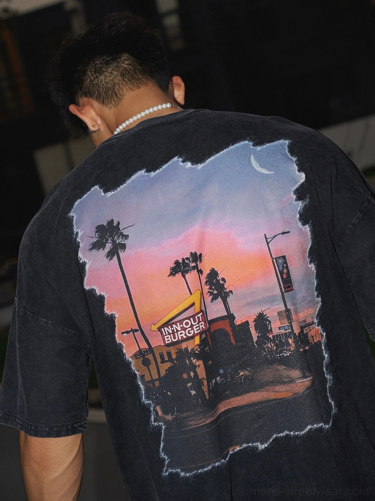 Back close-up of washed black oversized streetwear t-shirt featuring distressed retro diner sunset and palm tree graphic