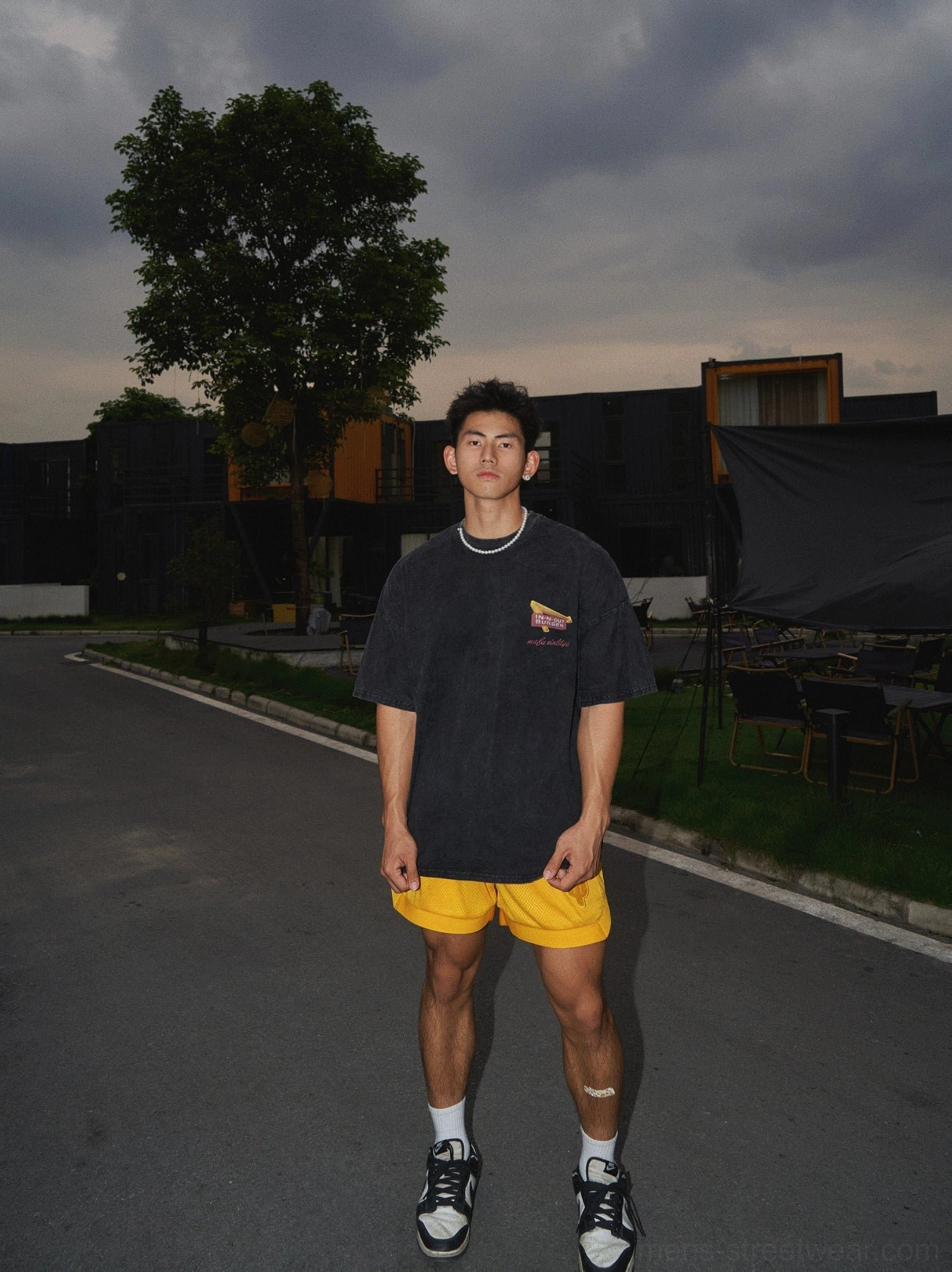 Full body streetwear outfit featuring washed black sunset palm graphic oversized t-shirt with yellow shorts and sneakers