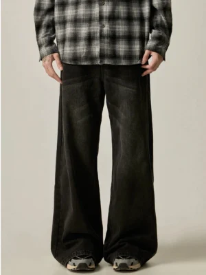 Front view of washed black ultra-wide leg jeans styled with a checkered shirt and retro running shoes in a neutral studio setting