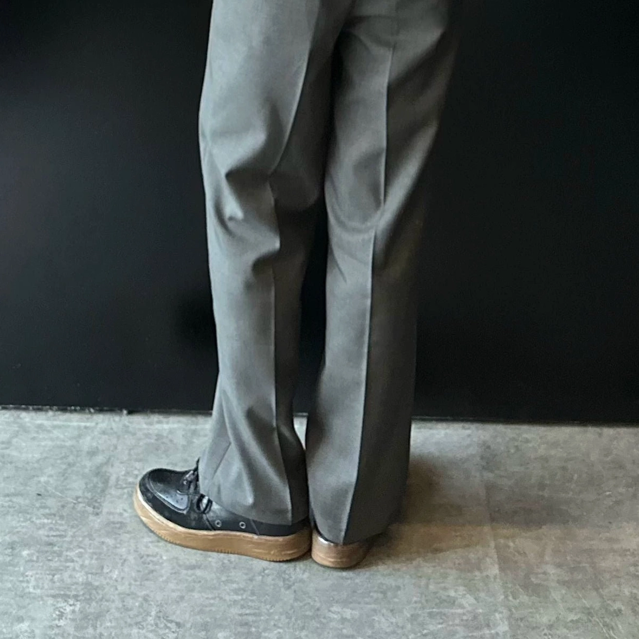 Rear side view of washed black vintage leather court sneakers showing heel tab, weathered leather finish, and contrasting brown gum rubber outsole