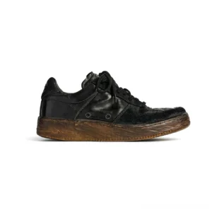 Side profile of washed black vintage leather court sneakers with textured horsehide upper, black laces, perforated toe box, and distressed brown gum rubber outsole