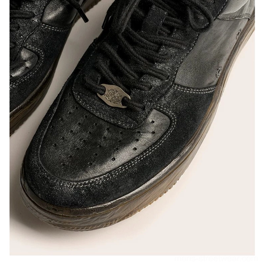 Close-up overhead view of washed black vintage leather court sneakers with perforated toe cap, metal lace detail, textured leather, and aged brown sole