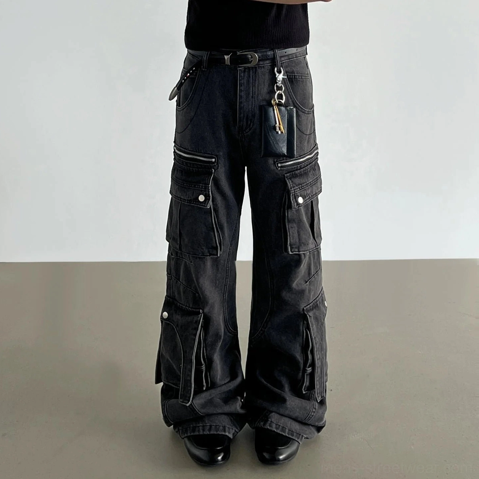 Washed black wide-leg cargo jeans worn in a low-angle front view with dimensional flap pockets and stacked streetwear silhouette