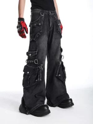 Side full-body view of washed black wide-leg cargo jeans with zippered utility pockets, adjustable buckle straps, metal hardware, and a relaxed Korean techwear silhouette