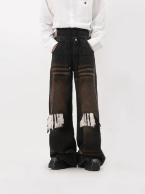 Front view of oversized wide leg streetwear jeans with layered waistband, striped waist accents, button closure, distressed faux fur knee patches and black platform boots
