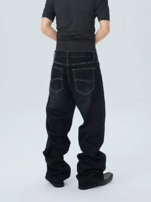 Rear view of washed black wide leg streetwear jeans showing twin back pockets, contrast stitching, relaxed mid rise fit and stacked hems over black boots