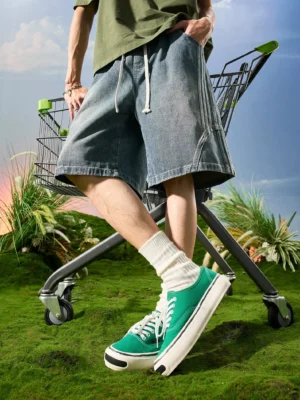Vintage washed blue baggy denim shorts with curved panel seams and drawstring waist styled with a green streetwear outfit outdoors