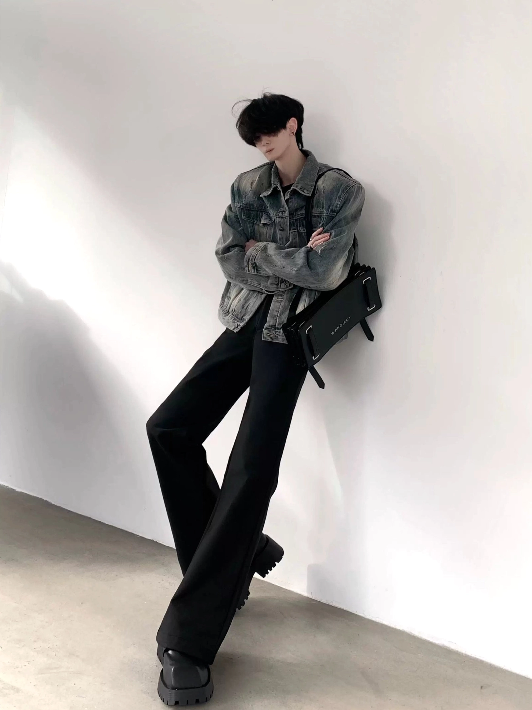Washed blue denim shoulder pad jacket in side front full body streetwear outfit with black flared trousers and platform shoes