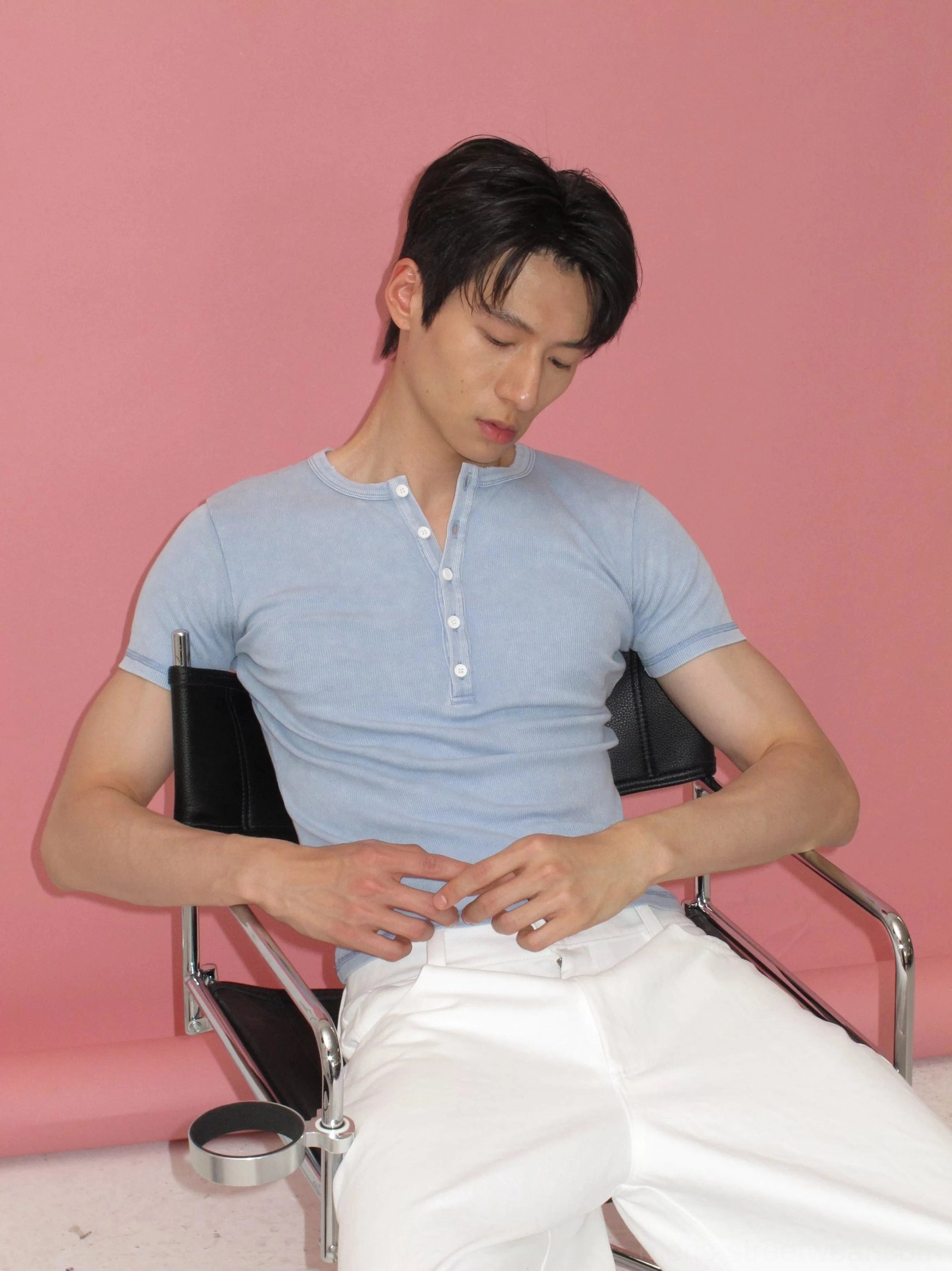Washed blue men's Henley streetwear tee shown from a seated front view with fitted ribbed fabric, distressed neckline, and button placket