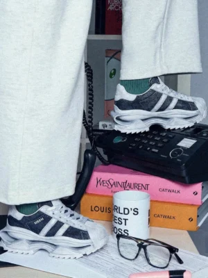Pair of washed blue leather platform sneakers styled with light grey sweatpants and vintage-inspired accessories in a streetwear flat lay