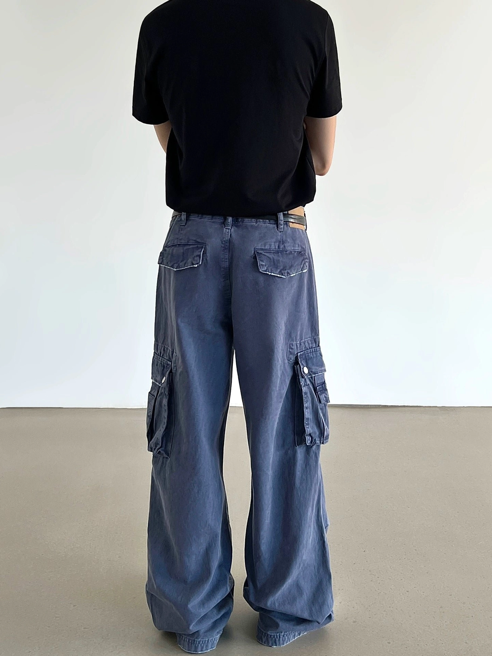Back view of washed blue wide-leg cargo pants featuring rear flap pockets, side cargo pockets, and a relaxed streetwear silhouette