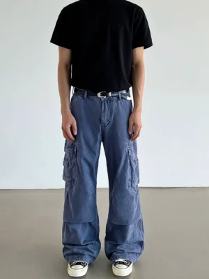 Front full view of loose washed blue cargo pants with wide straight legs, thigh flap pockets, black t-shirt, and sneakers