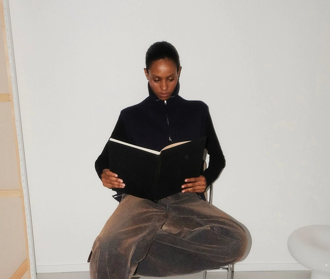 Washed brown high waisted flare jeans seated full body view with soft draped wide leg denim fit