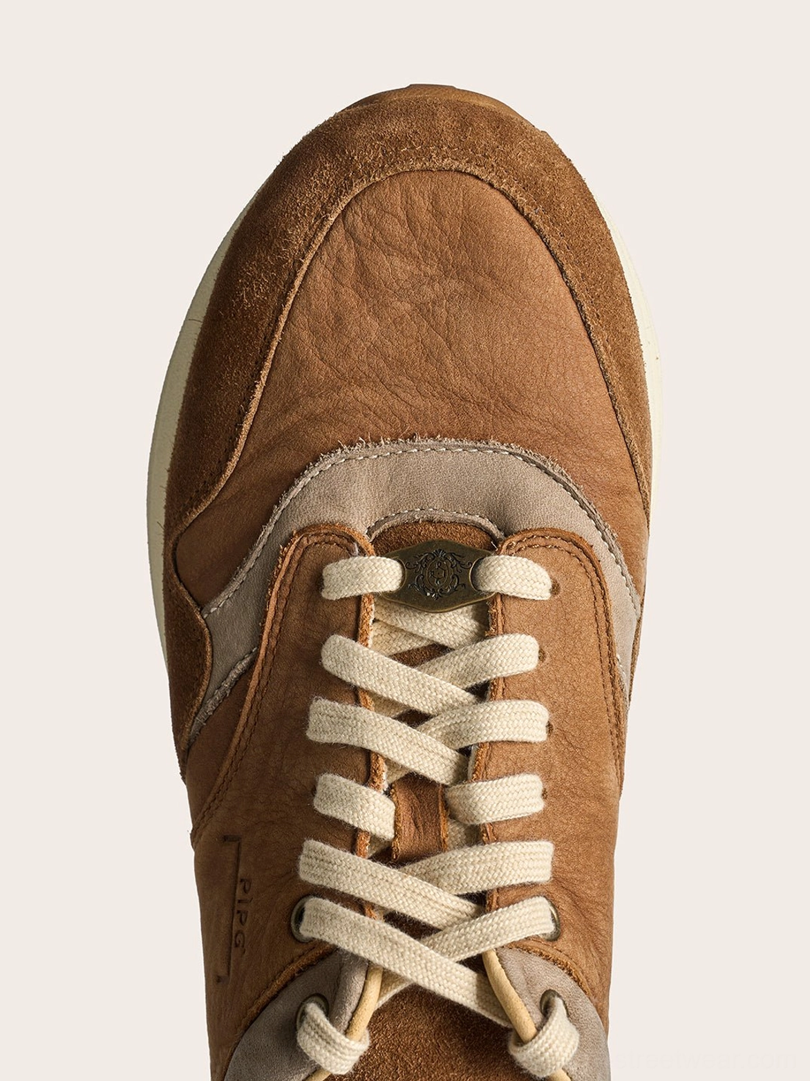 Brown low-top trail runner sneakers with distressed tonal suede, cotton laces, and contemporary gorpcore appeal