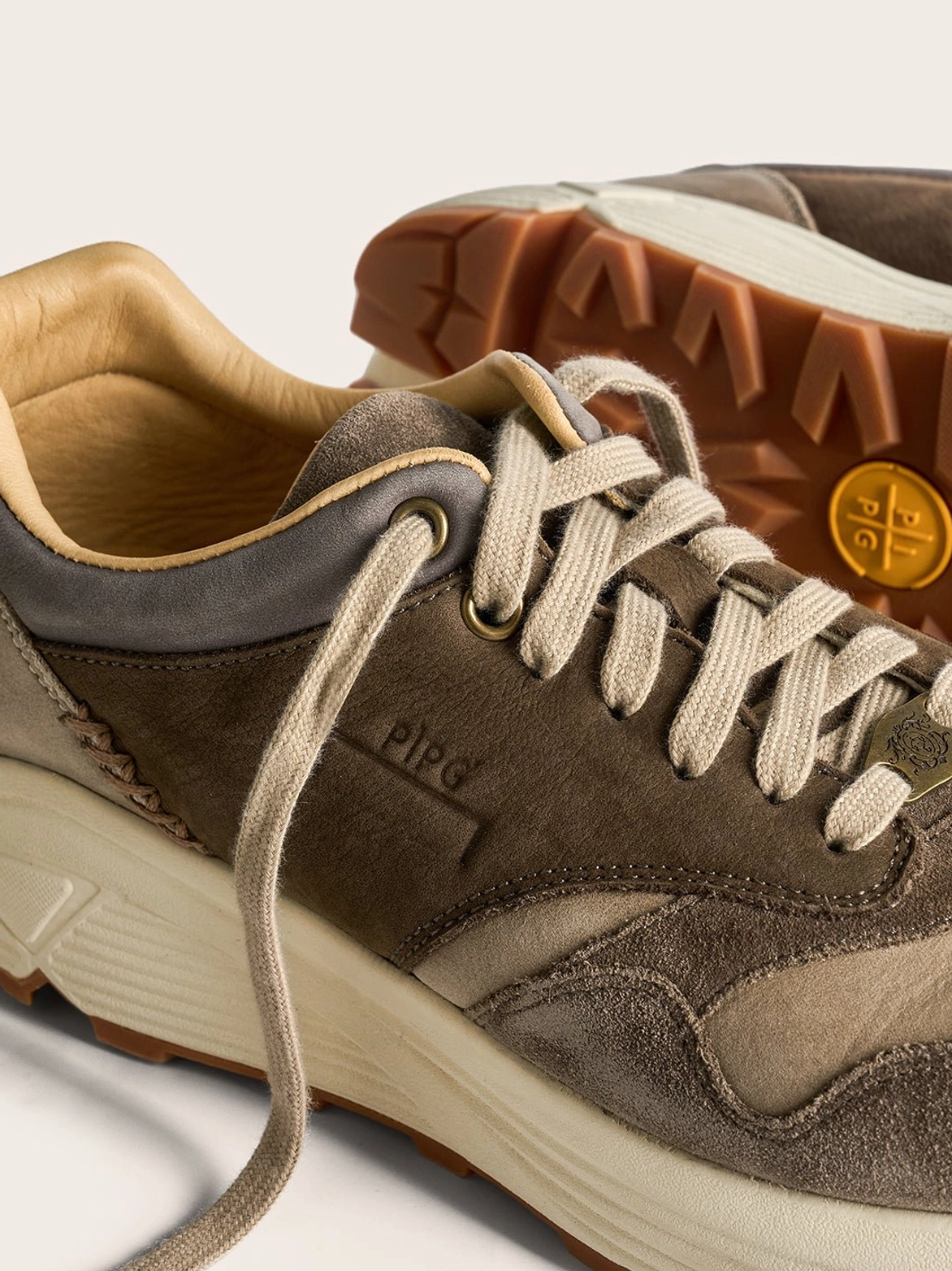 Side rear view of brown retro trail runner sneakers with tan lining, stitched heel details, and gum rubber outsole
