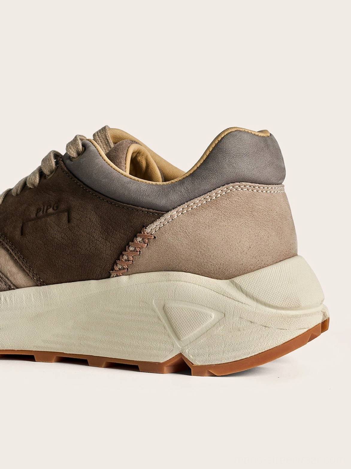 Side profile of washed brown retro trail runner sneakers with an off-white midsole and textured gum outsole